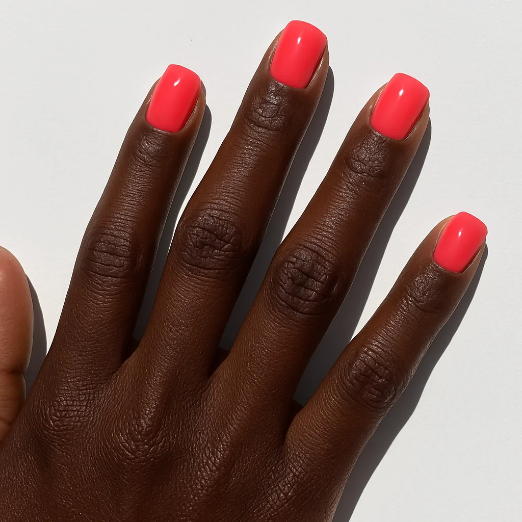 Short square neon coral pink ultra glossy nails on deep dark skin in direct sunlight — bold summer nail 2026